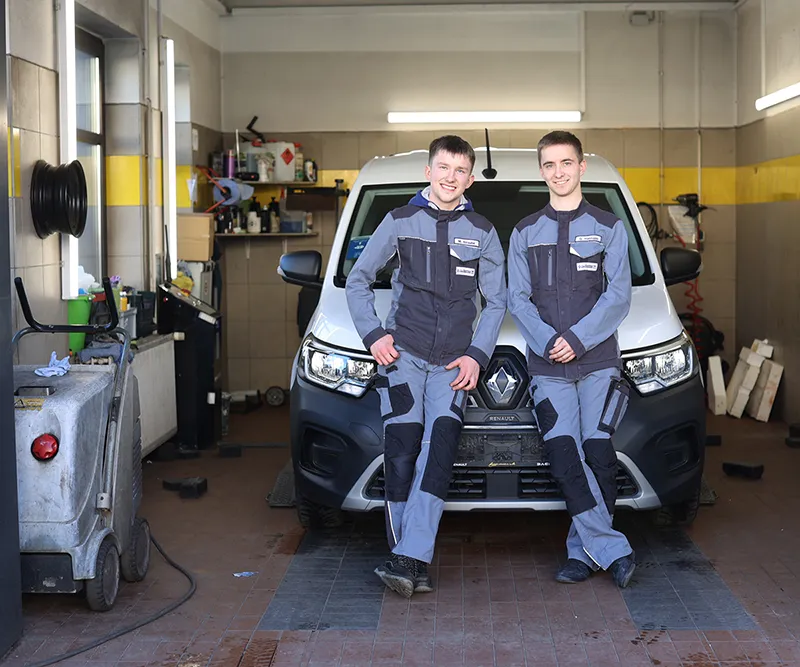 Azubis lehnen an einem Auto