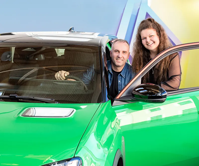 zwei Personen an einem grünen Auto